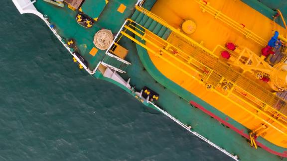 Top view of cargo logistics carrier ship cruising on the sea.