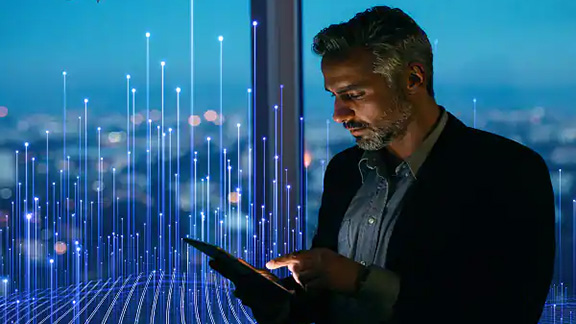 A man with a blazer using tablet near window of a building