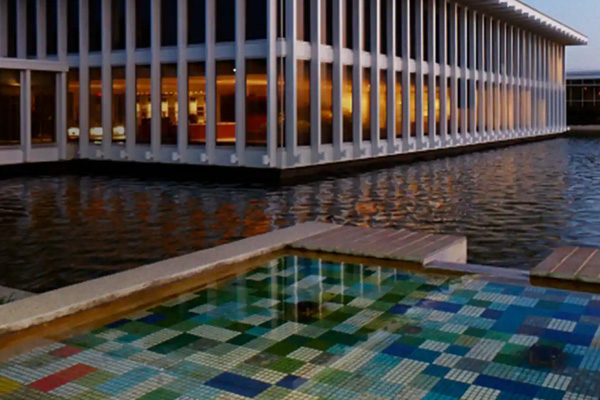 Two people sitting on sofas in a waiting room with wall clocks behind them