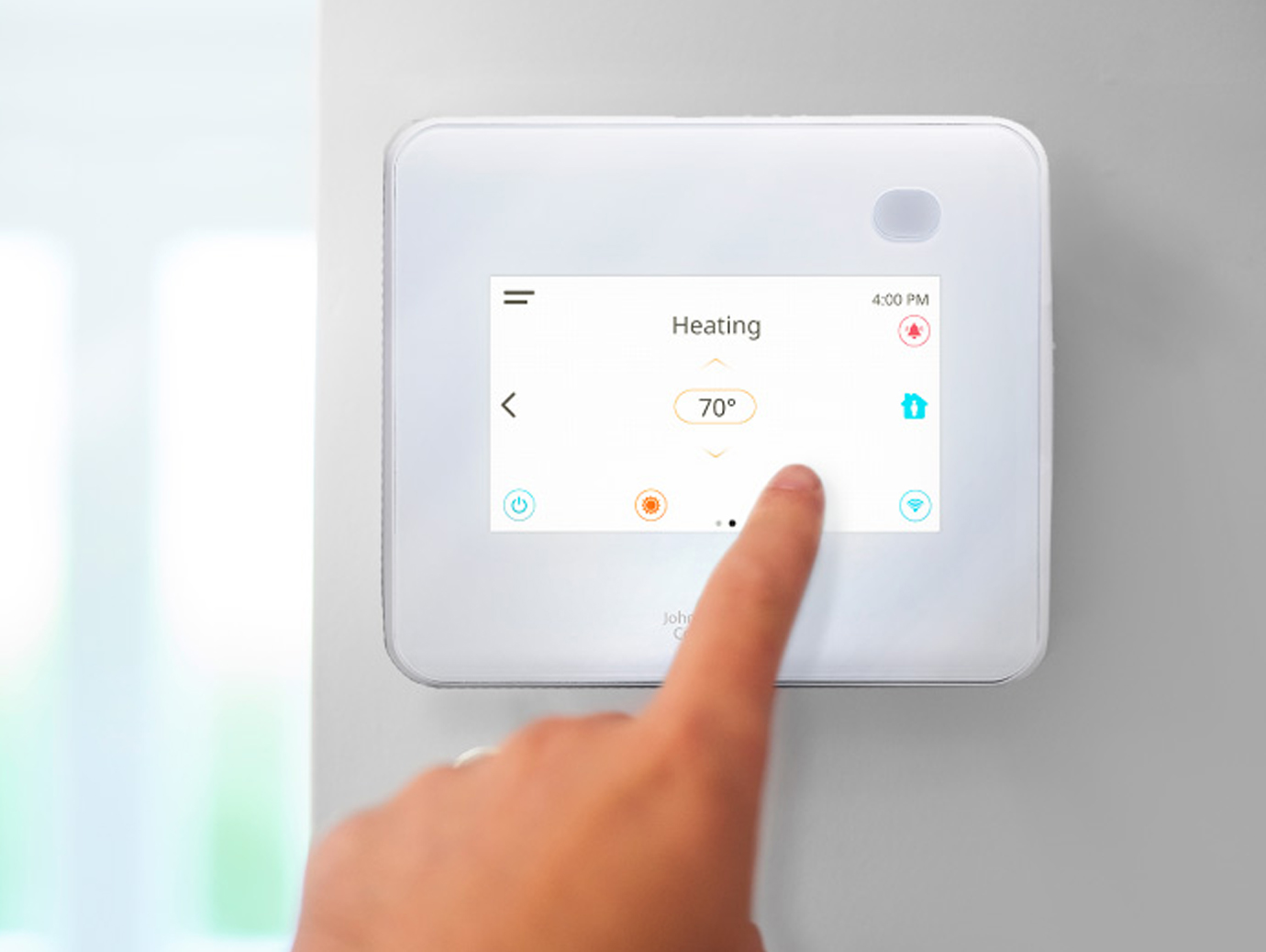 Close-up of a person operating a white networked thermostat on a wall
