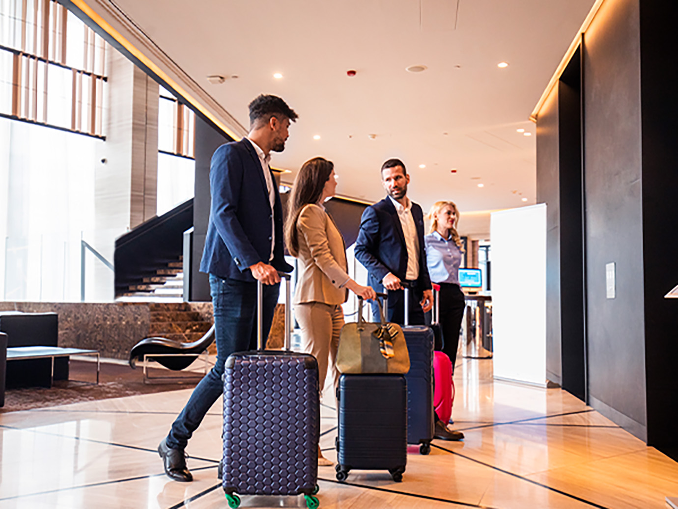 Four people in conversation standing in front of the elevators in a hotel lobby