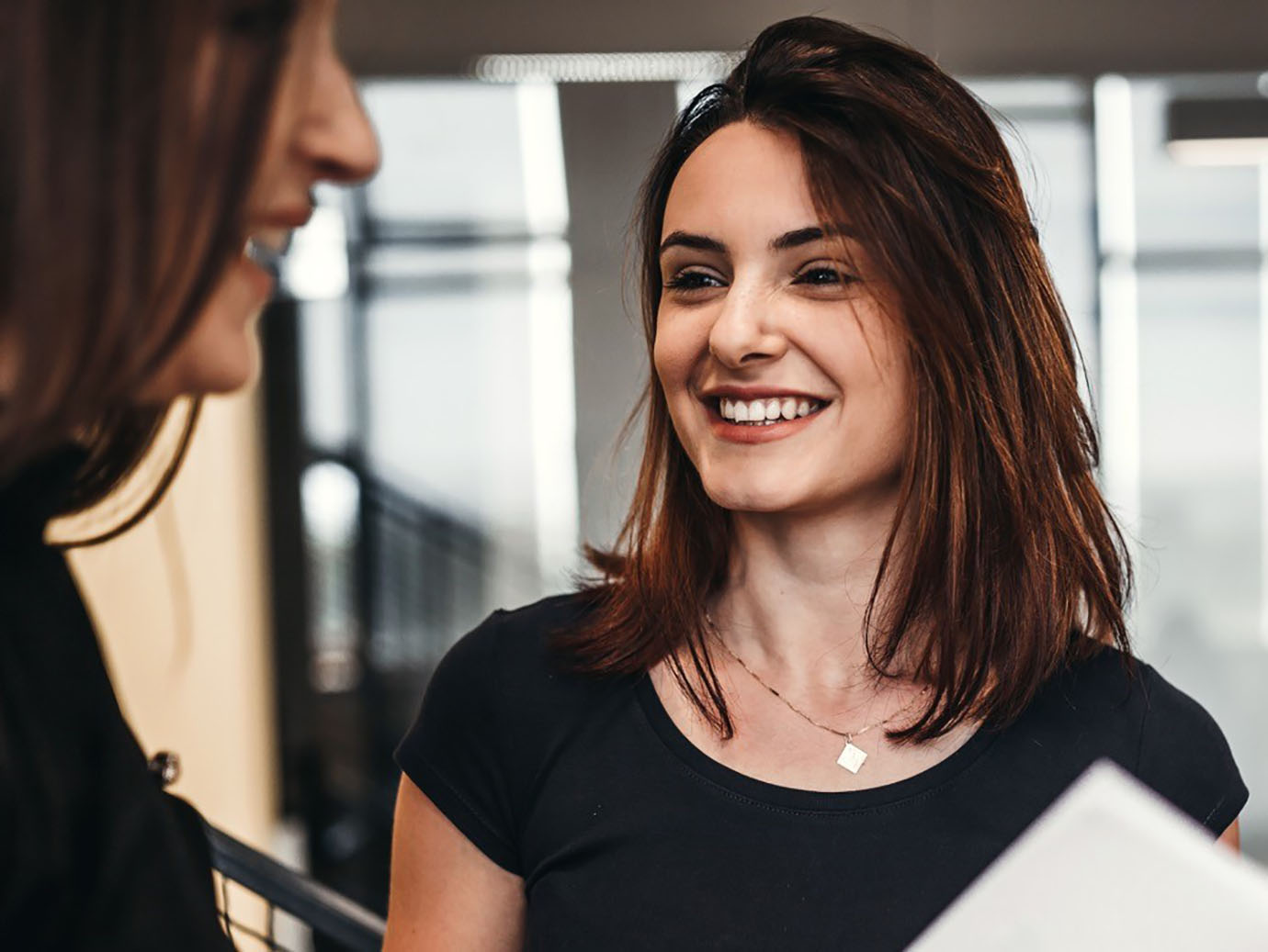 Two women smiling while having a conversation