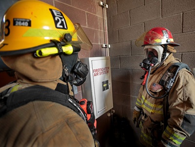 two firefighters discussing near firefighter air systems box