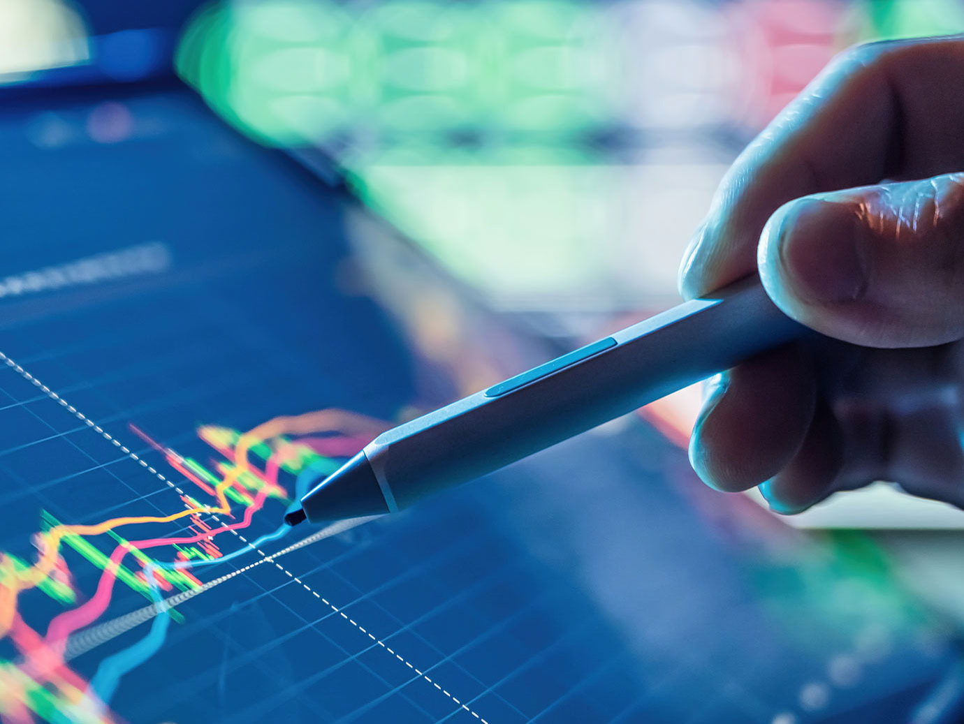 Close-up of a person pointing a stylus at a screen displaying a line graph