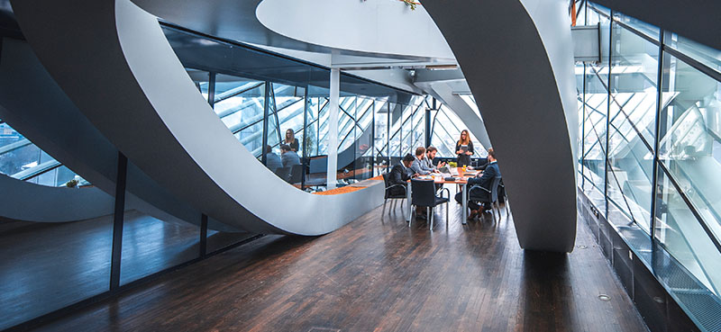 Interior of an office, where employees are seated a table in discussion.