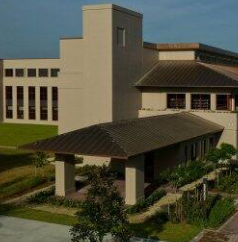 A building along a gravel path, surrounded by greenery