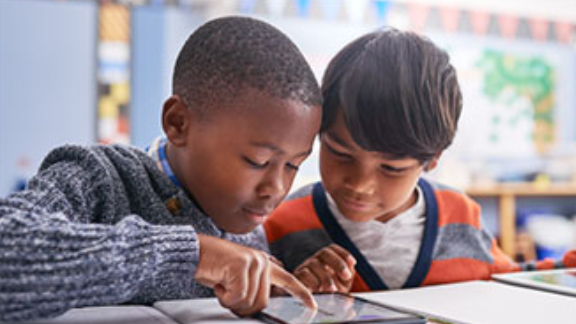 Two children looking at a tablet on a table