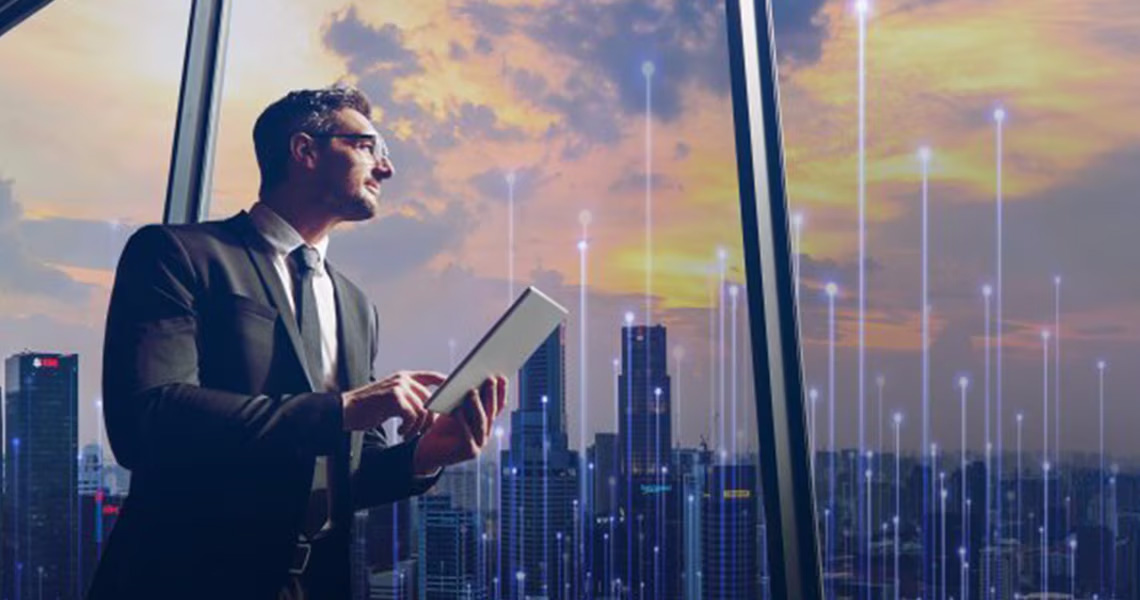 Man in formals working on a tablet and looking at a cityscape outside the window