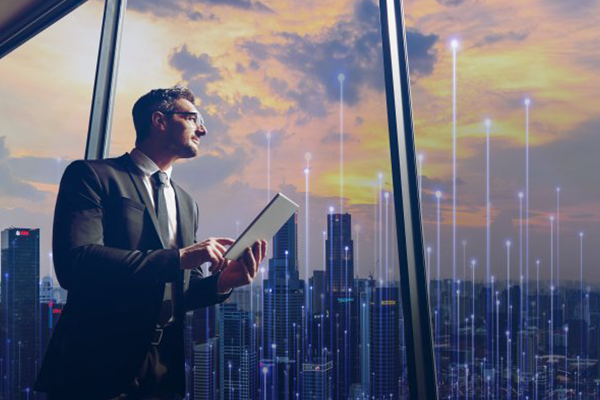 Man in formals working on a tablet and looking at a cityscape outside the window