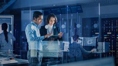 Man and woman looking at a tablet screen in a data center while others work in the background