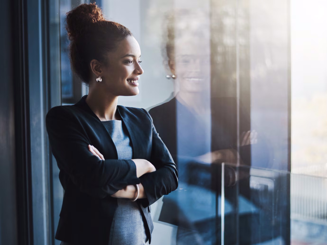 Woman in a suit smiling looking out a window