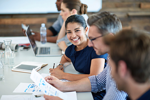 Five people sitting at a conference table, with one smiling at the camera