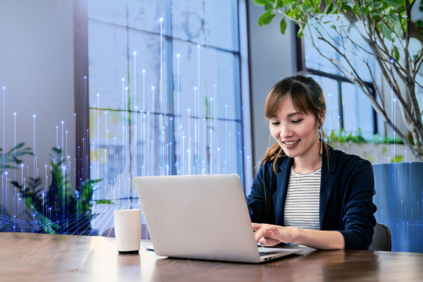 A woman smiling as she works on her laptop in an office, surrounded by OpenBlue graphics
