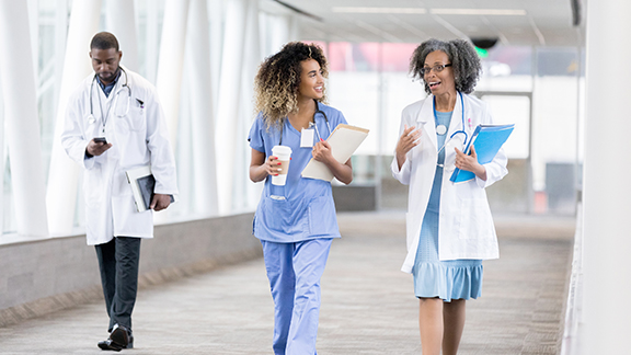 Doctors and nurses conversing and walking along a passage in a hospital