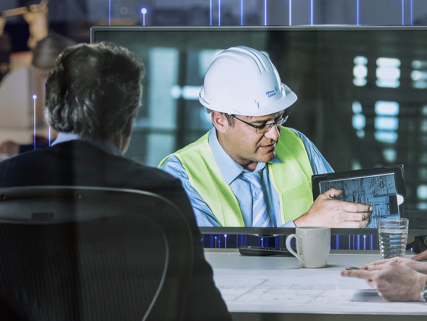 A group of employees on a video call with a maintenance engineer, who is demonstrating something on a tablet