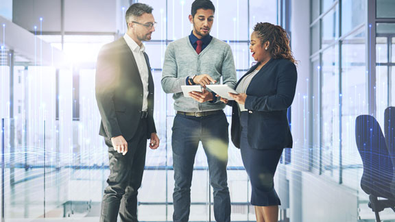 Two men and a woman standing and chatting in an office passage