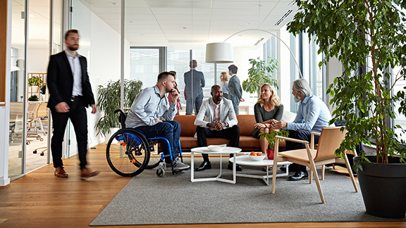 A group of employees sitting on a couch in an office and conversing