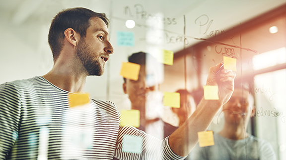 A man looking at a sticky note on a glass wall