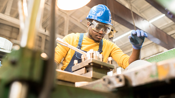 An engineer in protective gear working in a factory