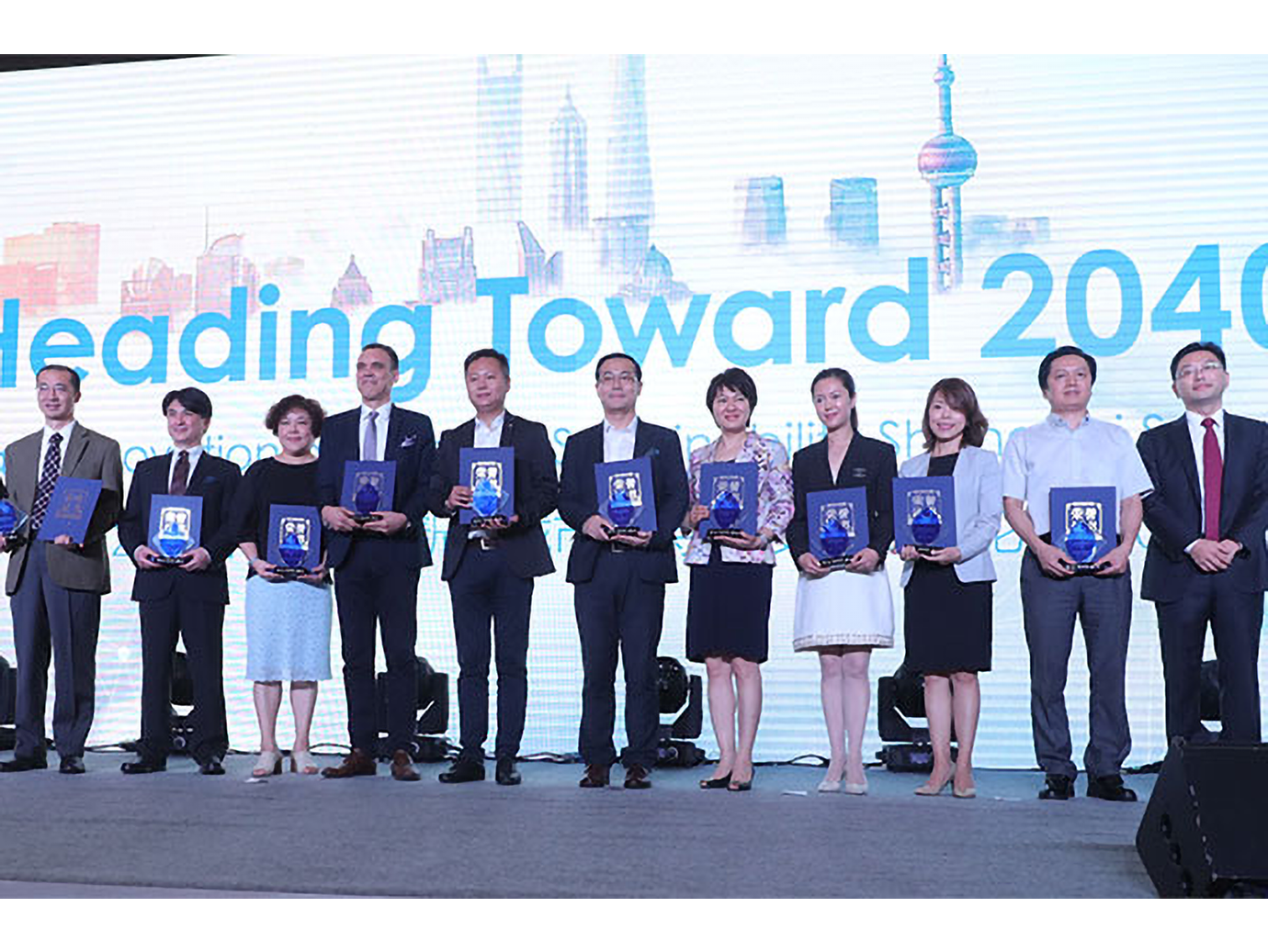 A group of people standing in line on a stage holding a plaque