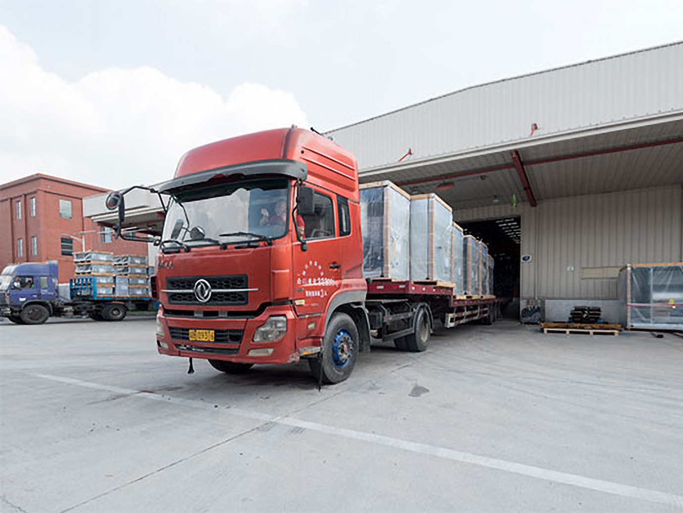 A truck carrying huge boxes of products leaving a building